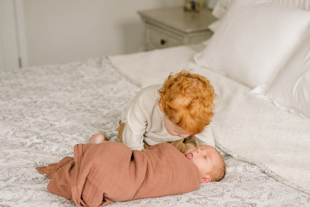 toddler gives kisses to new baby brother |  Newborn Photos with Toddler with Janet Winter Photography