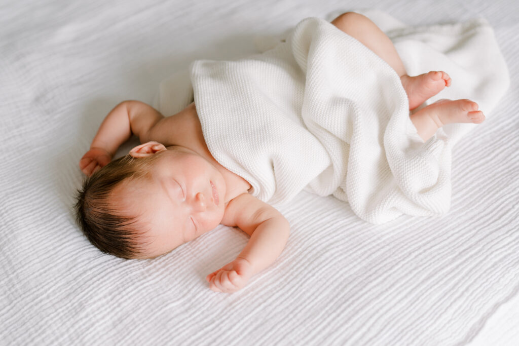 photo of baby girl during newborn photos on bed alone