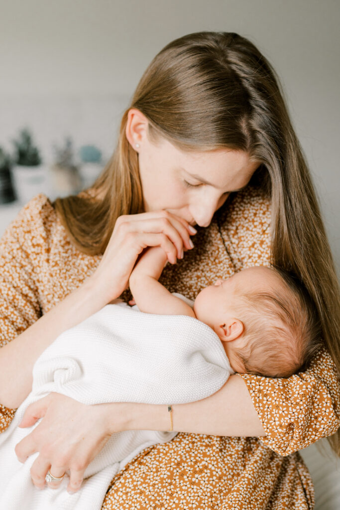 mom snuggles newborn baby during in-home newborn photos