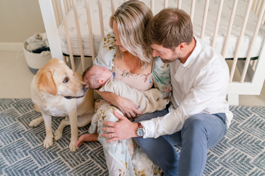 Charleston Newborn Photographer - mom and dad sit in front of crib during newborn photoshoot with dog