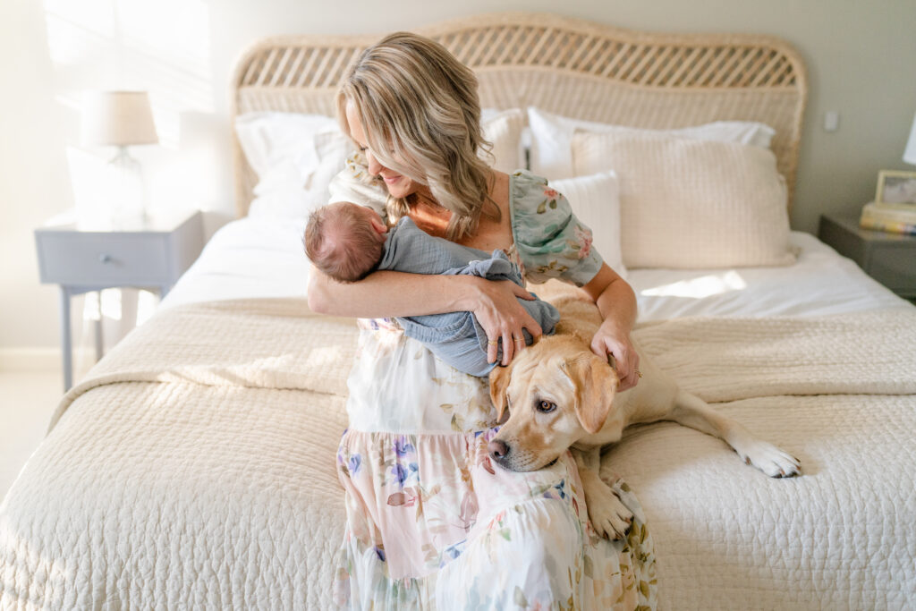 Charleston Newborn Photographer - mom, baby and dog snuggling on bed during newborn photoshoot